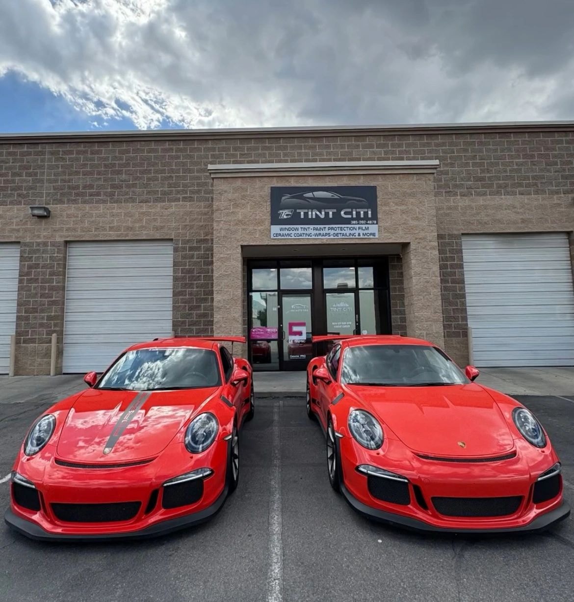 Two red Porsche sports cars in Tint Citi Utah showroom after window tinting and PPF service